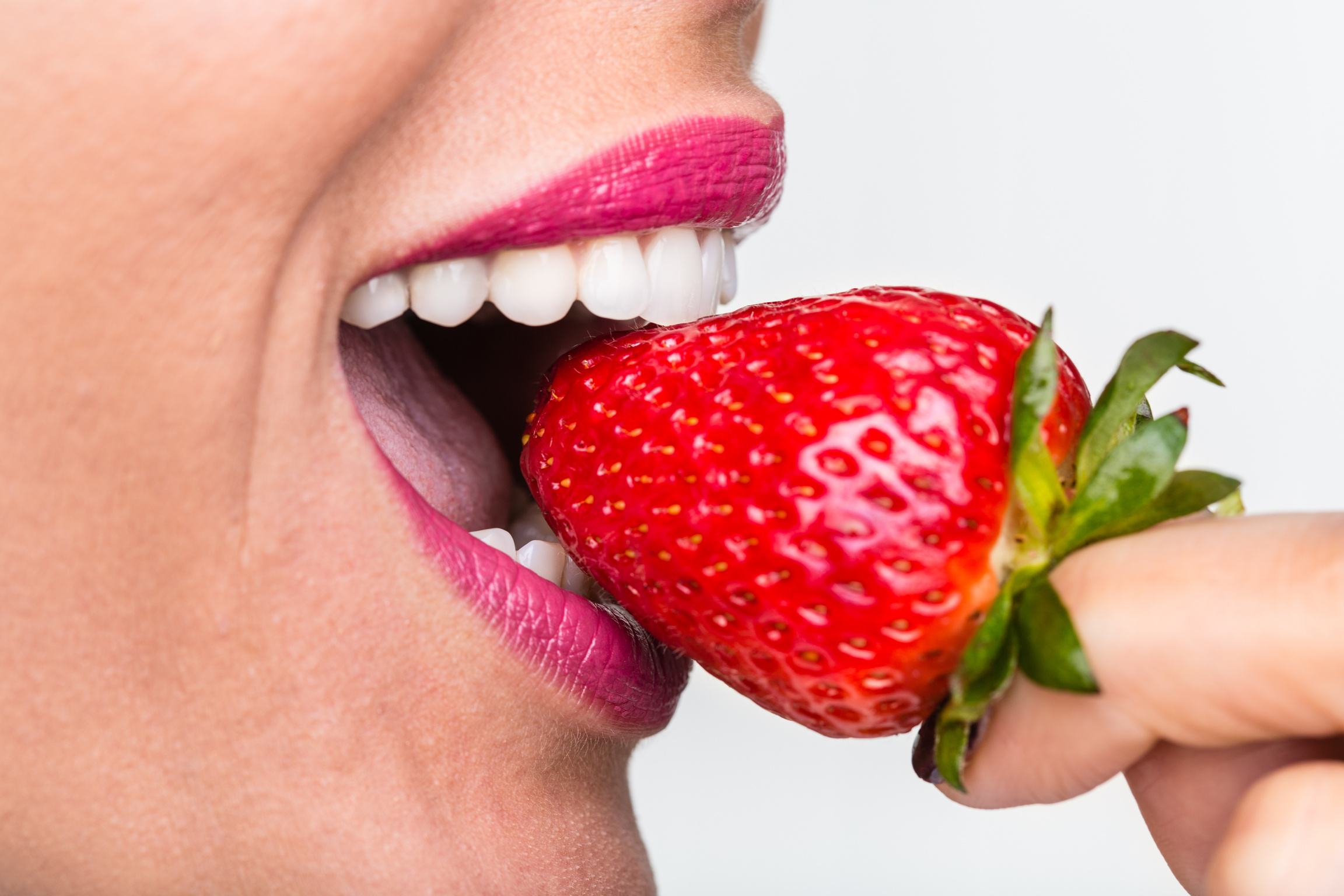 Healthy teeth biting strawberry